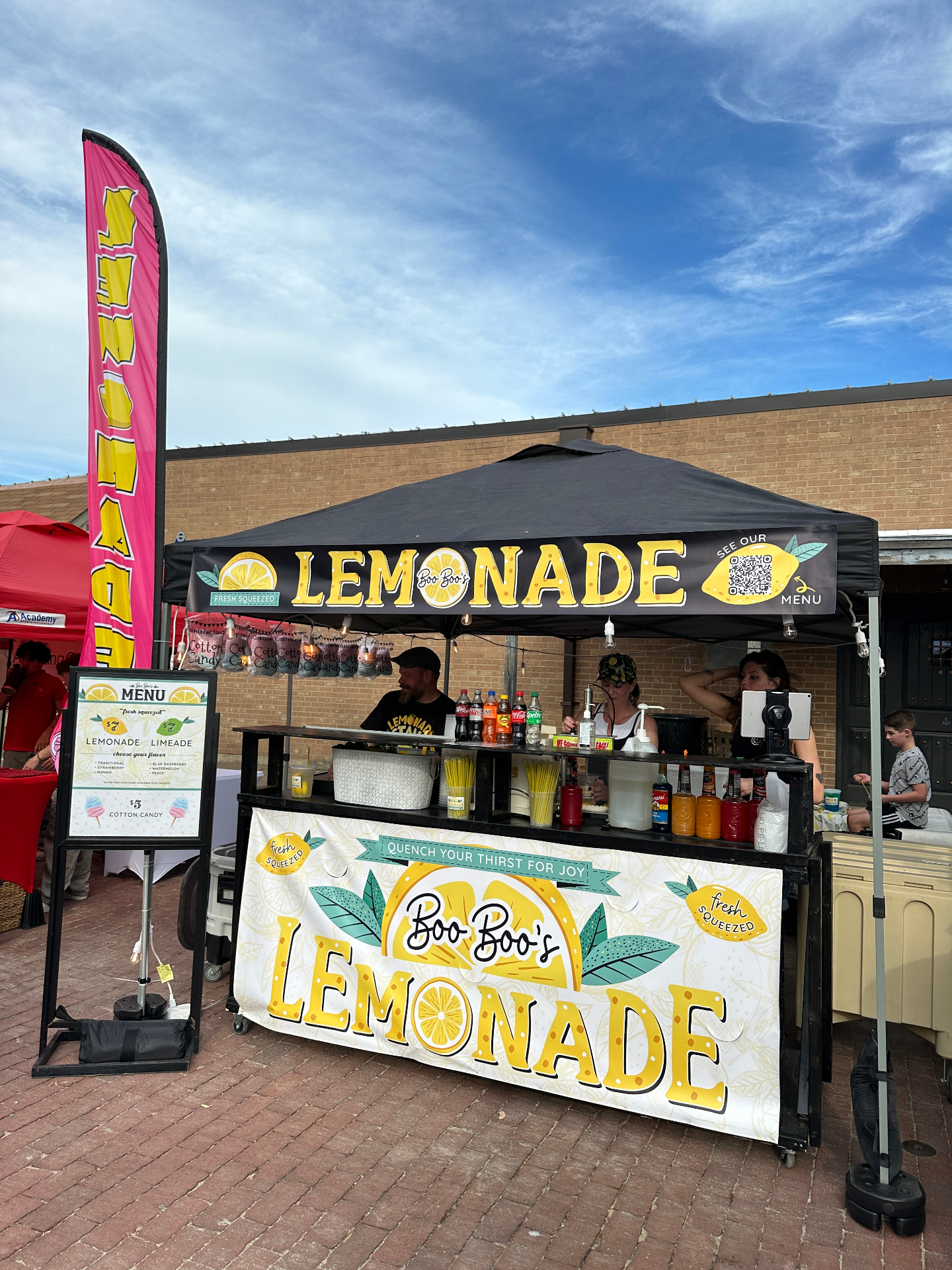 Black canopy market setup with menu stand and pink flag
