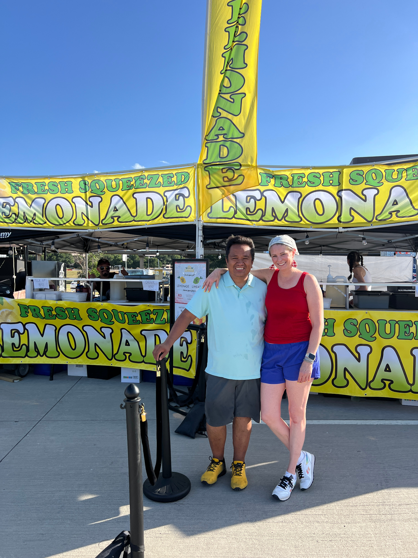 Owners posing in front of fresh squeezed lemonade banners