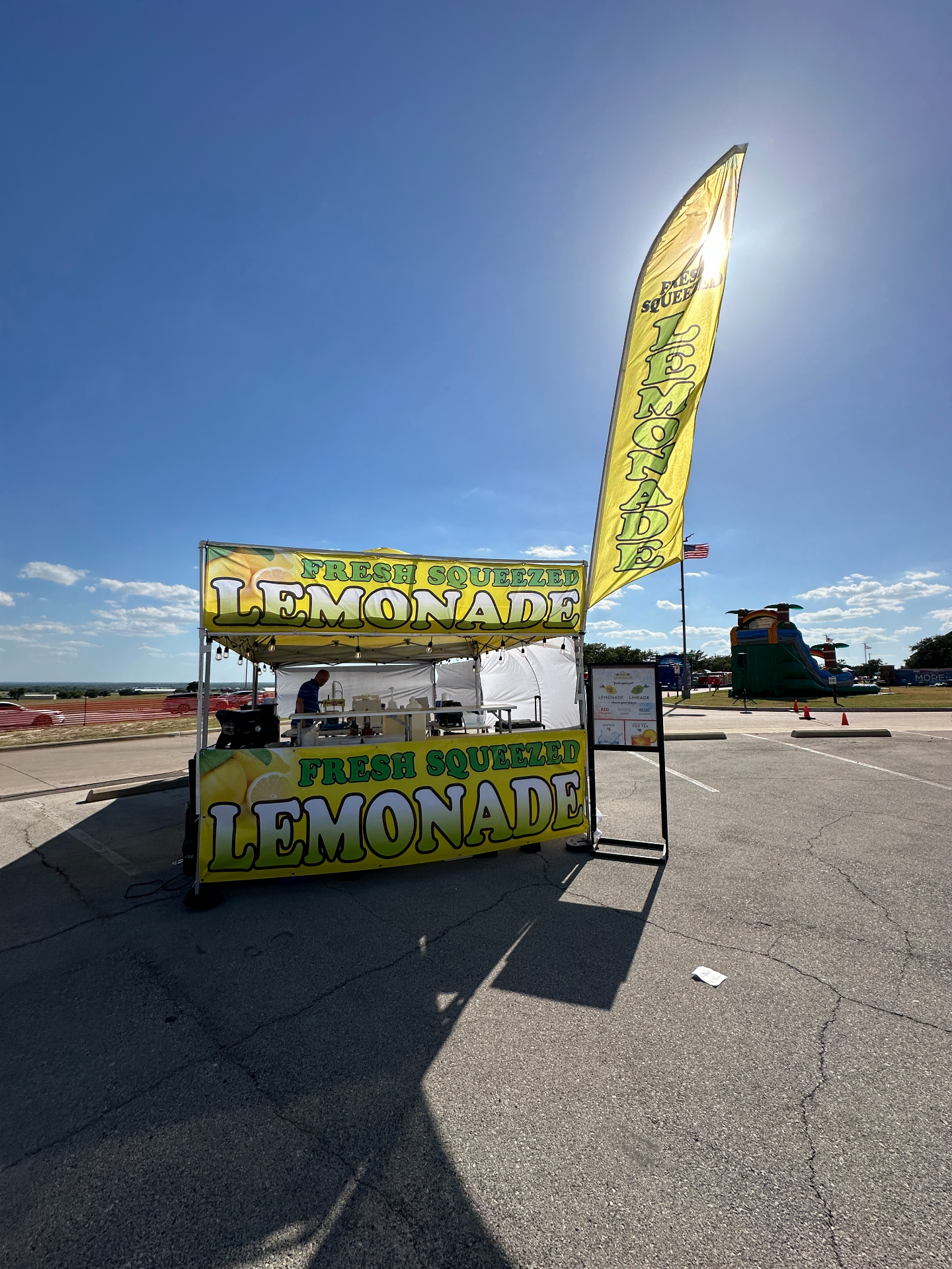 Wide open-lot lemonade stand with tall flag