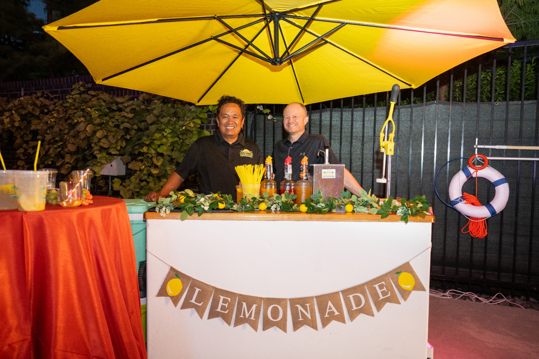 Owners smiling behind the lemonade bar at night