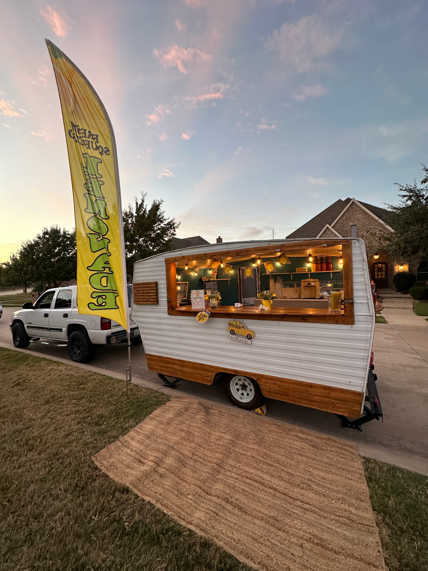 Vintage lemonade trailer setup at dusk in a neighborhood