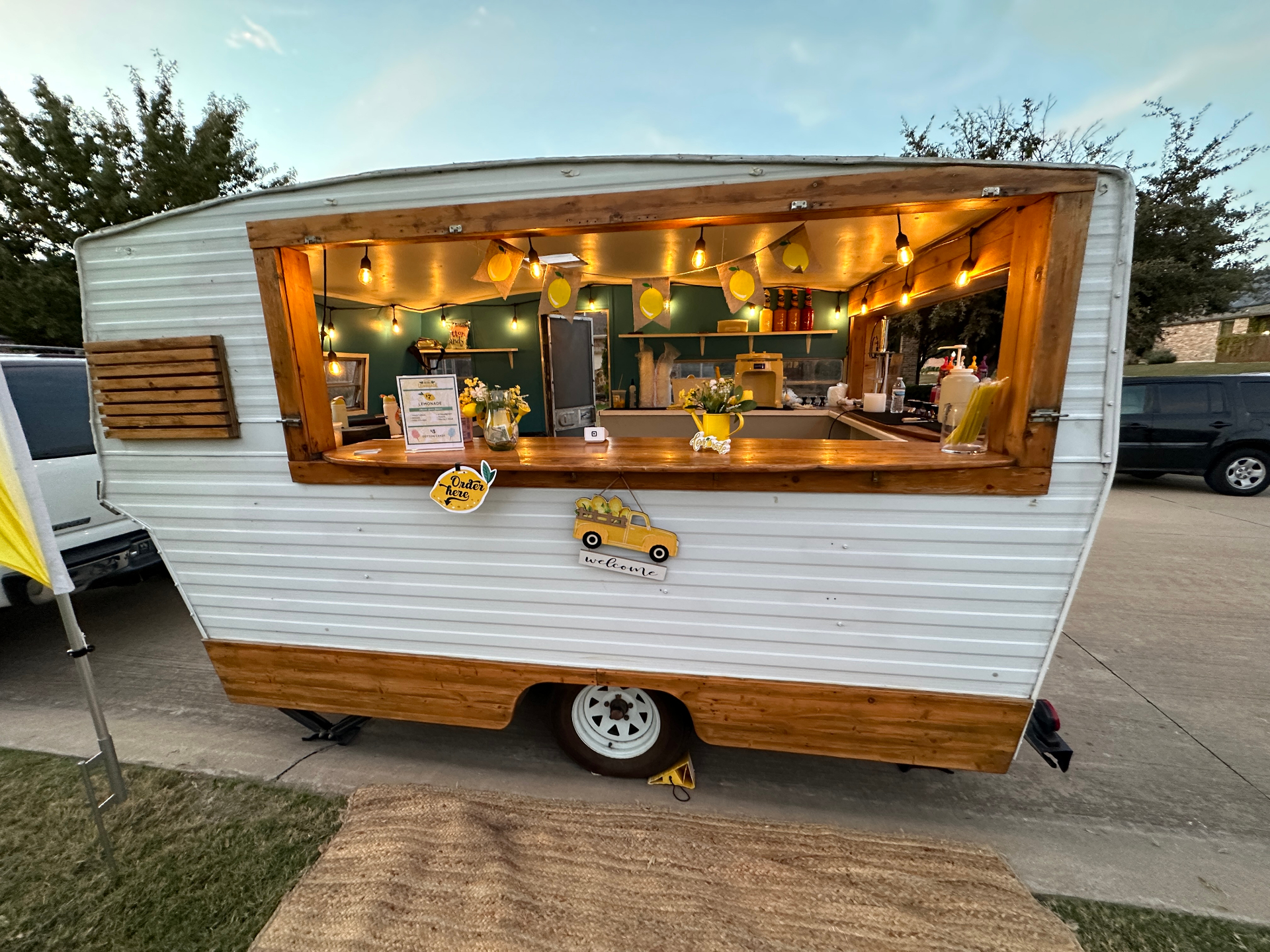Open service window of vintage trailer with string lights